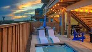 A wooden deck with lounge chairs, a pool, and a barbecue area. - 2 Homes, Sleeps 22 | 2 Private Pools, Firepit, Steps to Beach Boardwalk Access (Port Aransas)