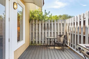 Una terraza de madera con una mesa y sillas, una puerta blanca y una valla de madera.