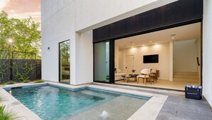 Ein modernes Haus mit Schwimmbad, einer Terrasse und einem Wohnzimmer mit Sofa und Couchtisch.