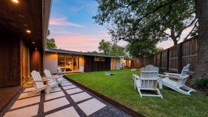 A backyard with a wooden deck, white Adirondack chairs, and a well-maintained lawn. - 4BDR House w/ Pool & Guest House in Central Austin (Austin)