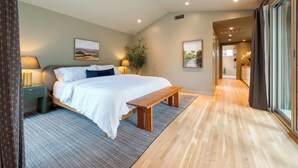 A bedroom with a bed, bedside tables, a bench, a ceiling fan, and a view of a hallway. - 4BDR House w/ Pool & Guest House in Central Austin (Austin)