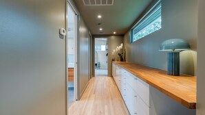 A modern hallway with a wooden floor, a built-in bench, and a wall-mounted lamp. - 4BDR House w/ Pool & Guest House in Central Austin (Austin)