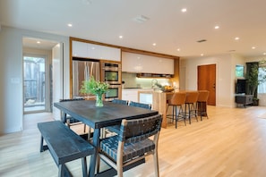 Eine moderne Küche mit Holzschränken, Edelstahlgeräten und einem Essbereich mit einem dunklen Holztisch und Stühlen.