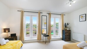 Une chambre d’hôtel avec deux lits, une petite table, une lampe, une commode et une fenêtre avec des rideaux.