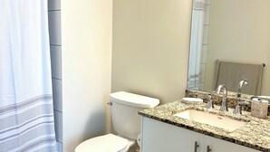 A bathroom with a toilet, sink, and mirror. - Beautiful Two-Bedroom Escape Ocean & City Views from Every Room (San Diego)