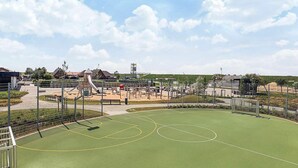 A sports court with a basketball hoop and a playground area with various play structures. - 4 Star Holiday Home in Friedrichkoog (Friedrichskoog)