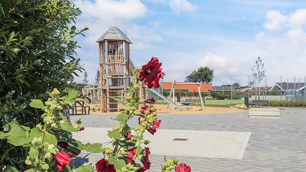 Une aire de jeux avec une structure d’escalade en bois et une balançoire.