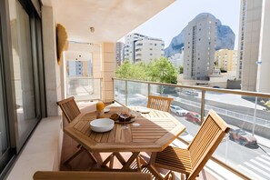 A balcony with a wooden table, chairs, and a glass railing.