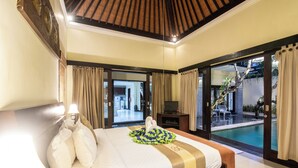 A hotel room with a large bed, a TV, and a view of a swimming pool. - 5BR Private Pool Tiga Samudra Villa (2Units Villa) (badung)