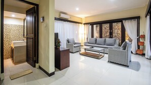 A modern living room with a sofa, armchairs, and a coffee table. There is a window with curtains, a lamp, and a small table with a plant. - 5BR Private Pool Tiga Samudra Villa (2Units Villa) (badung)