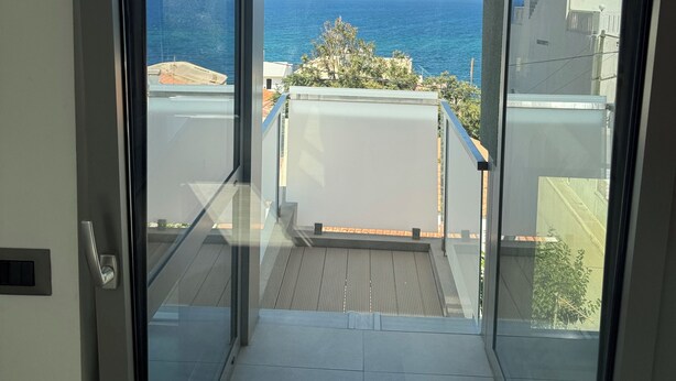 A modern apartment with a balcony overlooking a coastal view.