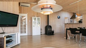 Un salon moderne doté d’un téléviseur à écran plat, d’une cheminée, d’un coin repas avec des chaises et d’un plafond en bois.