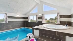 A modern bathroom with a large bathtub, a separate shower area, and a small pool.