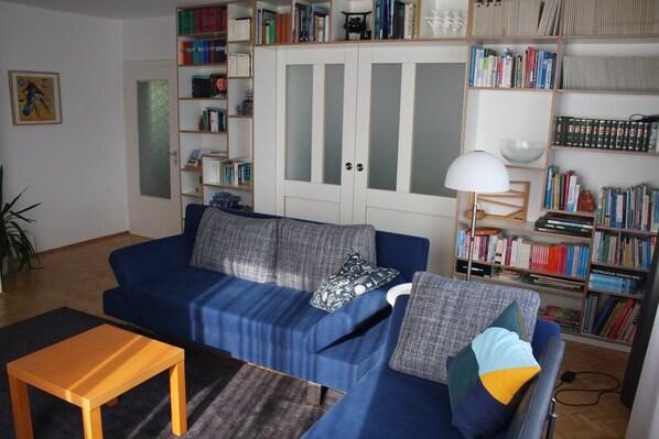 Un salon avec un canapé bleu, une table basse en bois et une bibliothèque remplie de livres.