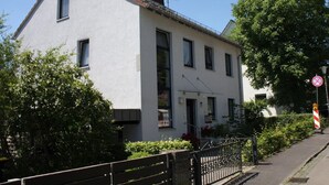 A two-story building with a white facade, a visible entrance, and a gated driveway.