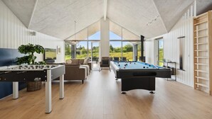 A spacious indoor area with a foosball table, a pool table, and a comfortable seating area with a view of the outdoors. - VillaVilla 598 - Rømø, Sydjylland (Rømø)