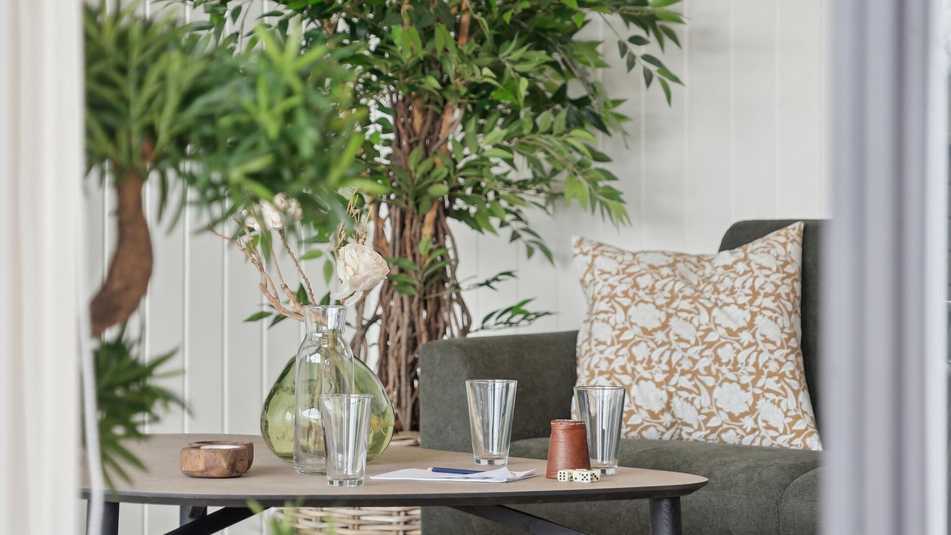 Une table avec un vase, des verres et un carnet.