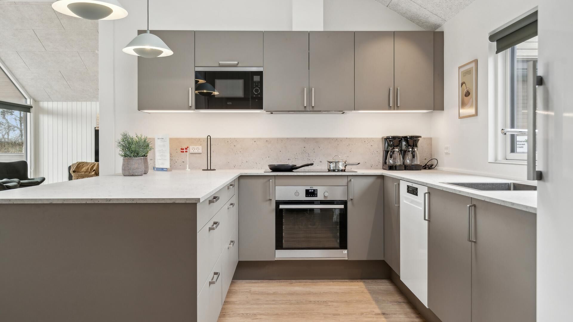 Una cocina moderna con gabinetes grises, horno empotrado, microondas y espacio para café.