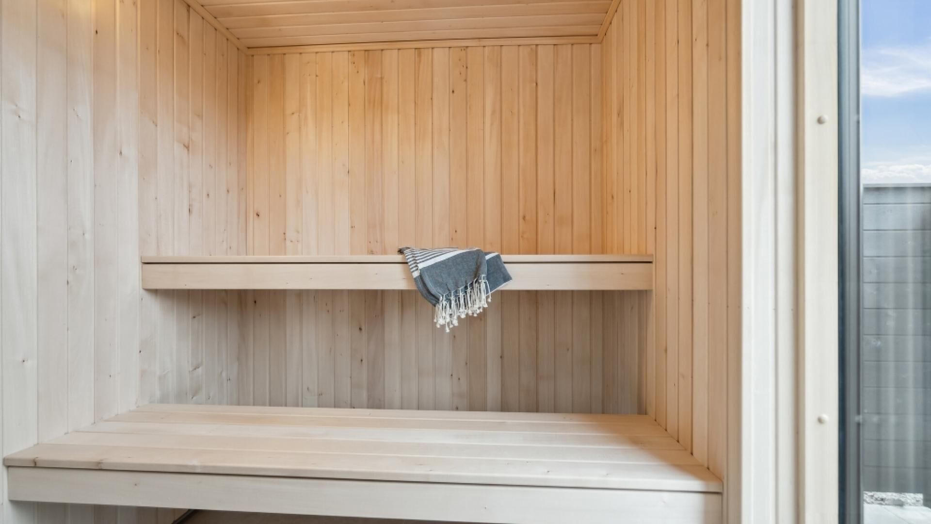 A sauna with a wooden interior, a bench, and a towel hanging on the wall.