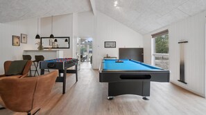 A modern indoor space with a foosball table, pool table, and a seating area with a brown leather chair. - VillaVilla 621 - Dueodde, Bornholm (Aakrikeby)