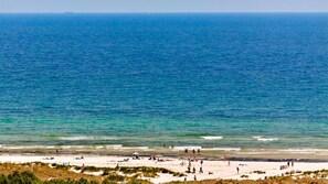Uma praia com pessoas e um navio ao longe.