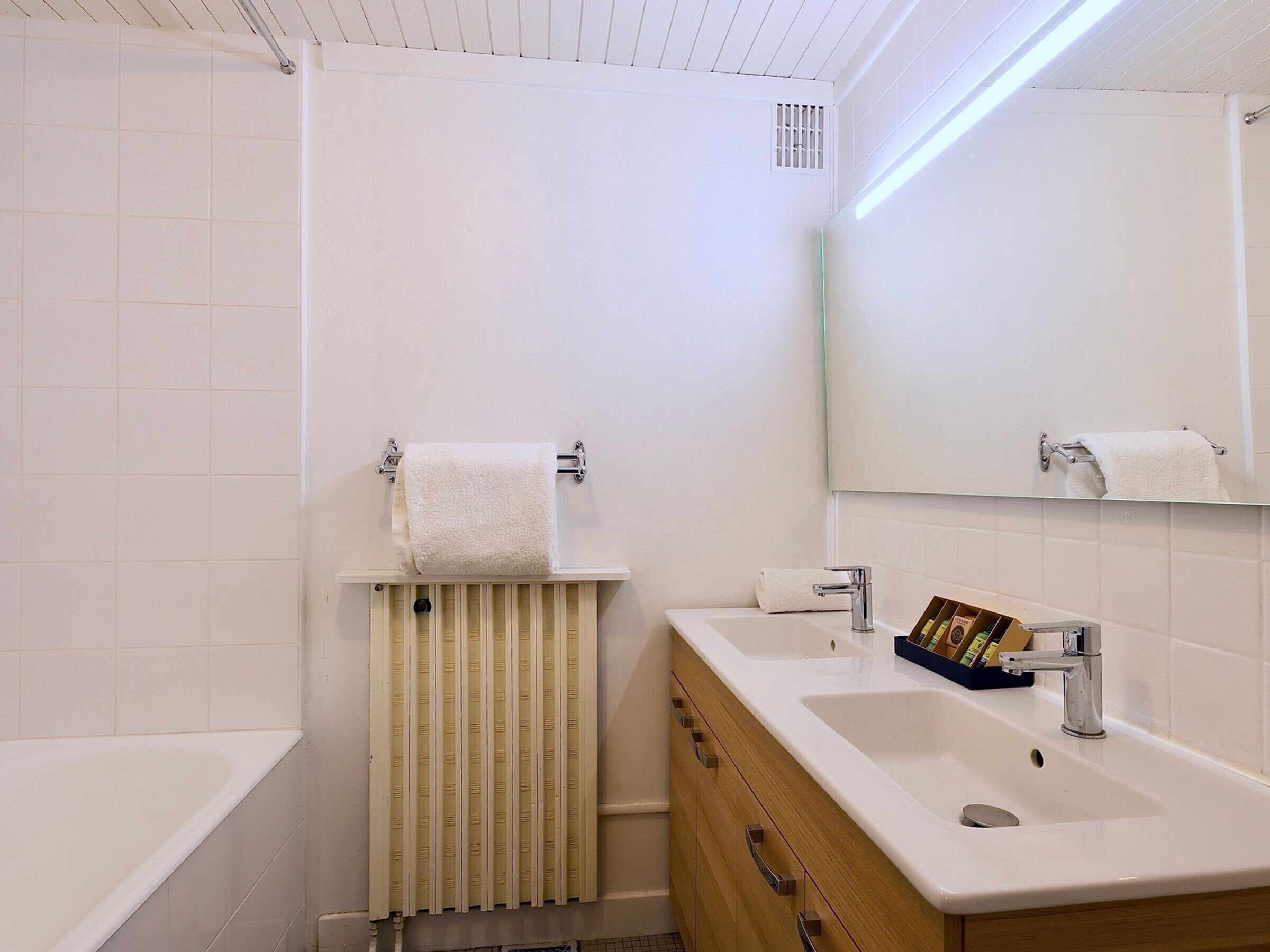 Une salle de bain moderne équipée d’une baignoire, d’un lavabo, d’un miroir et d’un porte-serviettes.
