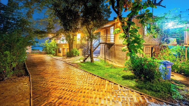 A well-lit pathway leading to a building with a staircase and a small garden area.
