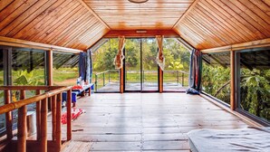 A wooden deck with a glass ceiling, offering a view of the surrounding greenery.