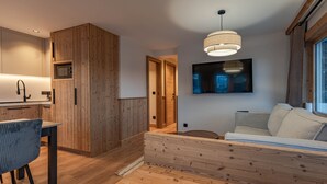 Una camera da letto moderna con un letto in legno, una TV a parete e un angolo cottura con mobili in legno e un forno a microonde.