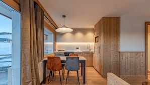 Una cucina moderna con mobili in legno, un'area pranzo con tavolo e sedie, e un'ampia finestra con tende.