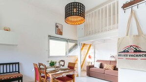 Uma sala de jantar com uma mesa posta para quatro pessoas, cadeiras de madeira, luminária pendente e uma janela com persianas.