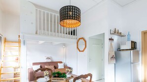 Apartamento moderno com área de refeições, cozinha e quarto no mezanino.