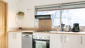 Uma cozinha moderna com armários brancos, lava-louças, forno e cafeteira.