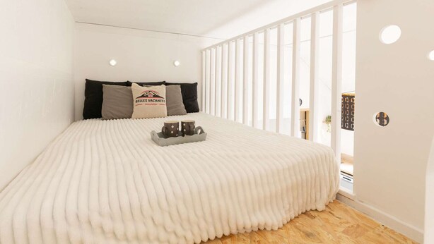Quarto com uma cama grande, cabeceira com logotipo e bandeja com duas canecas.