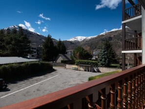 Vista de la montaña desde un balcón con barandilla de madera, un área de estacionamiento y edificios en primer plano.