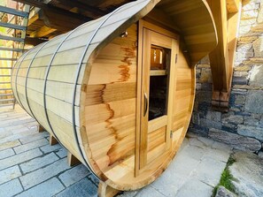 A wooden barrel-shaped room with a door, stone walls, and a stone floor.