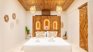 Un dormitorio moderno con techo de madera, una cama grande con ropa de cama blanca y apliques decorativos.