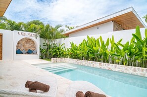 A pool area with lounge chairs and towels, surrounded by lush greenery and a stone wall with the name "LEK NA" visible. - 1Bedroom Villa Close to Fisherman KBR27 (Bophut)