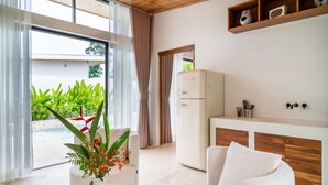 Una cocina moderna con refrigerador, un sofá blanco y una zona de comedor con encimera de madera.