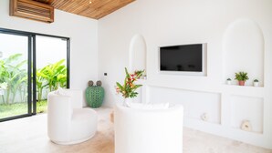 Una sala de estar moderna con un ventanal grande, sofás blancos, un televisor de pantalla plana y decoración minimalista.
