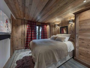 A wooden-paneled bedroom with a bed, a rug, and a mirror on the wall.