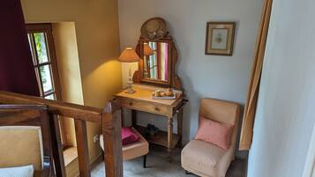 Une pièce avec un bureau en bois, une chaise, un miroir, un tableau encadré et une fenêtre.