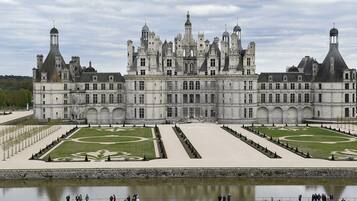 Un grand bâtiment historique doté de nombreuses tours et dont le jardin présente une disposition symétrique.