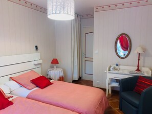 A hotel room with two beds, a desk, a chair, a mirror, and a hanging light fixture. - Eglantine Room: Charm in Loire Valley with Pool and Wifi (Tavers)