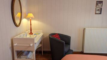 Une pièce comprenant un lit, un bureau avec une lampe, une chaise, un radiateur et une étagère avec divers objets.