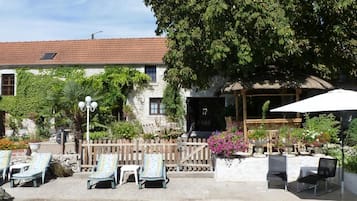 Un’area piscina con sedie a sdraio, una recinzione in legno e un edificio con tetto in tegole.