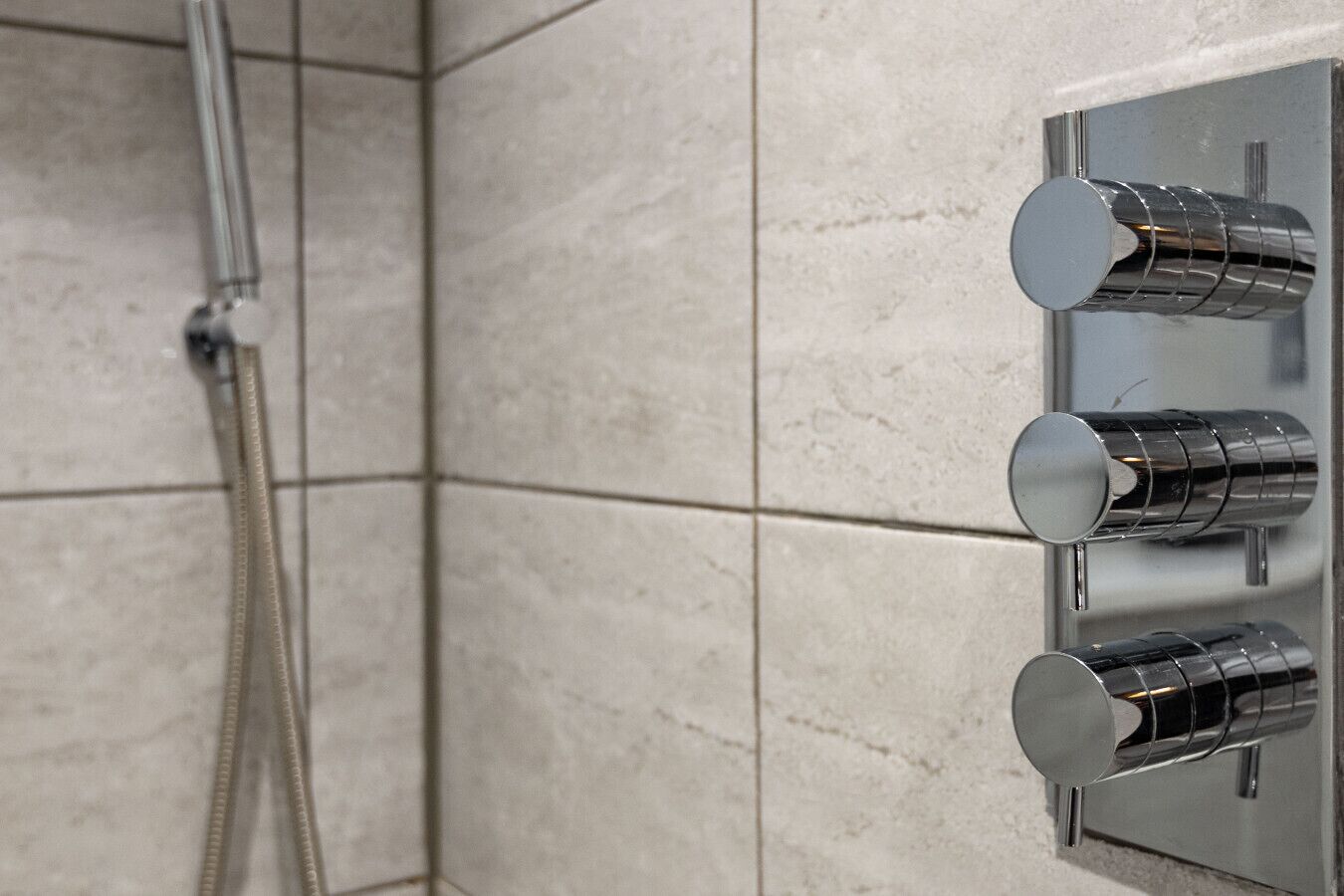 Une douche avec un robinet chromé et une pomme de douche à main.