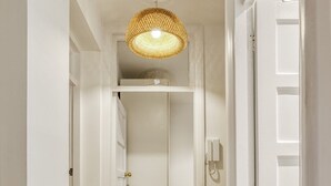 Un pasillo con suelo de madera, paredes blancas y una lámpara colgante.