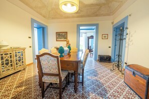 A dining room with a wooden table, chairs, and patterned floor tiles.