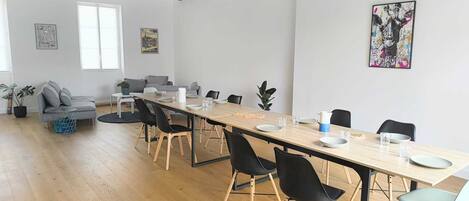Un espace de restauration moderne avec une longue table, des chaises noires et un plafond en bois.